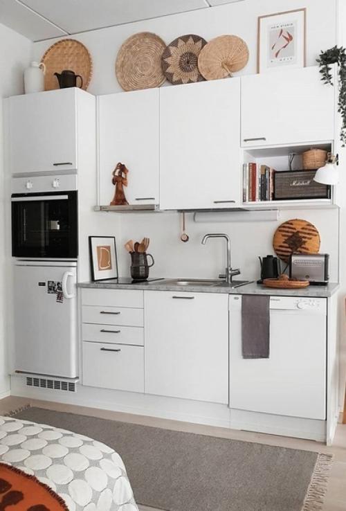 Кухня выполнена в светлом цвете, но имеет несколько тёмных деталей.