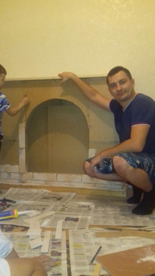Муж с юным помощником мастерят в квартиру декоративный камин. 02